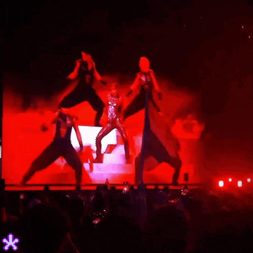 a group of people are dancing on a stage with red lights