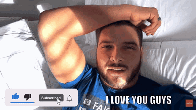 a man in a blue shirt is laying on a bed and says " i love you guys " at the bottom
