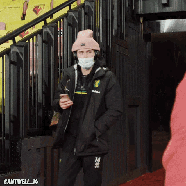 a man wearing a face mask and headphones is standing in front of a staircase with cantwell 14 written on the bottom