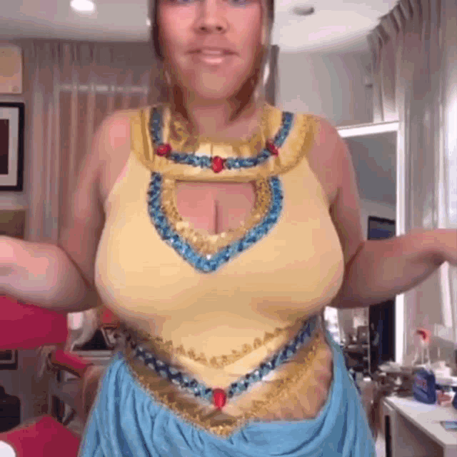 a woman in a yellow top and blue skirt is standing in a room .