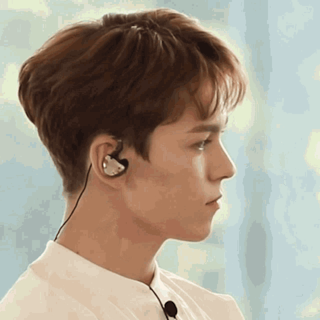 a young man wearing a pair of ear buds looks to the side