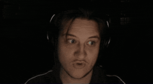 a man is wearing headphones in the dark and making a funny face .