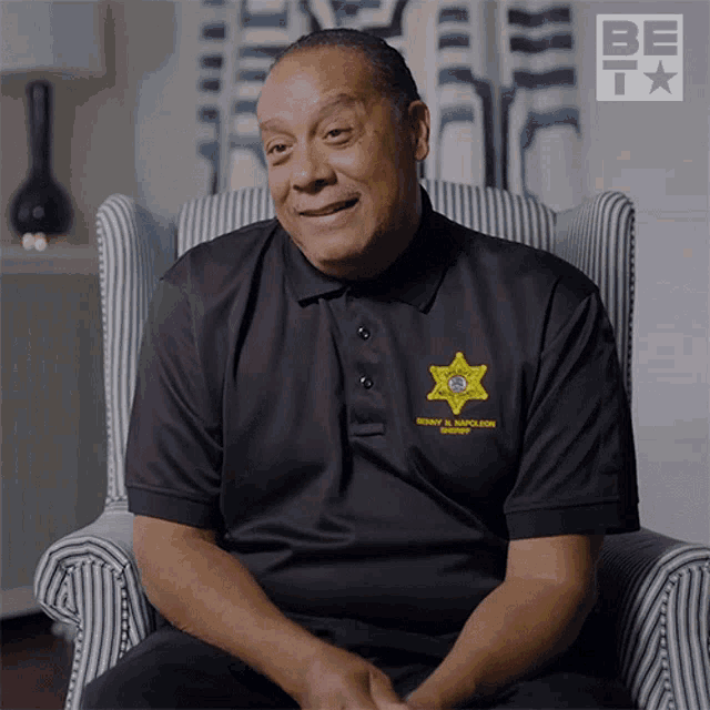 a man sitting in a chair wearing a berkeley sheriff 's badge