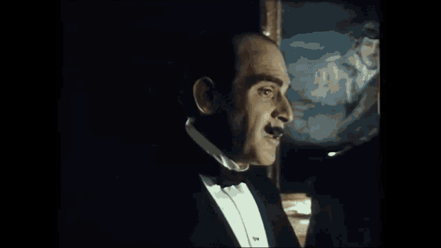 a man in a tuxedo with a mustache is giving a thumbs up sign .