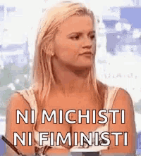 a woman is sitting in front of a window with the words ni michisti ni fiministi on her chest .