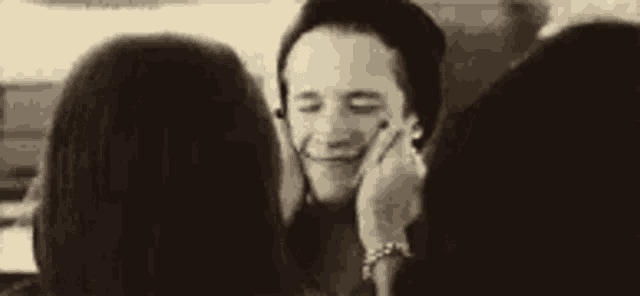 a woman is touching a man 's face while he laughs .