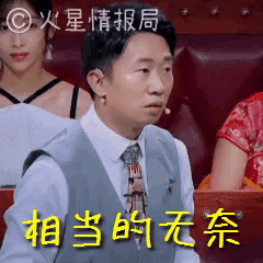 a man in a suit and tie is sitting in a theatre with chinese writing on the screen .