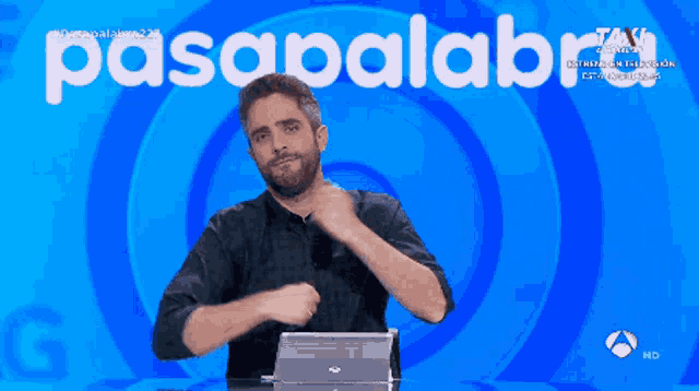 a man stands in front of a screen that says pasapalabra on it