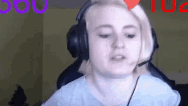 a woman wearing headphones and a microphone is sitting in a chair and making a funny face .