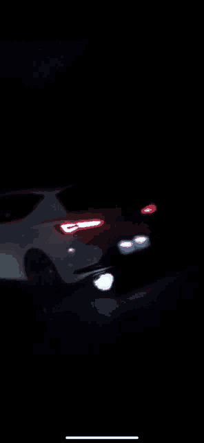 a white car is driving down a dark road