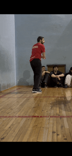 a man in a red shirt that says ' georgia ' on it is standing on a wooden floor