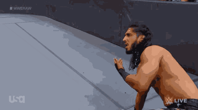 a shirtless wrestler is kneeling down in front of a usa logo