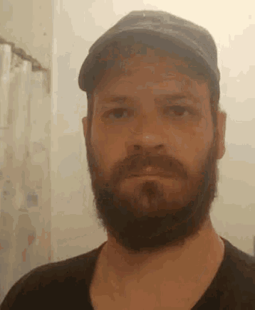 a man with a beard wearing a hat and a black shirt .