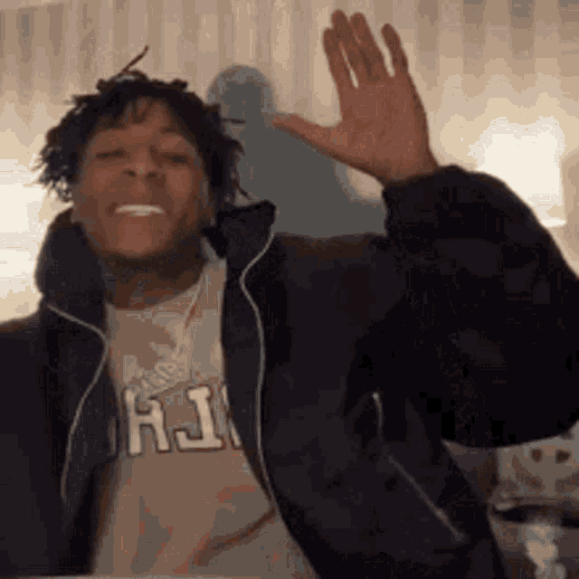 a man in a jacket is waving his hand in the air .