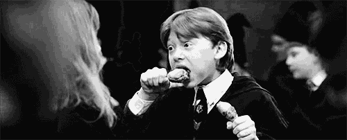 a black and white photo of a boy eating a piece of meat .