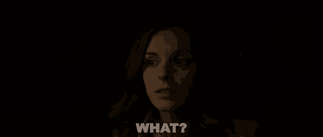 a woman in a dark room is asking the question " what "