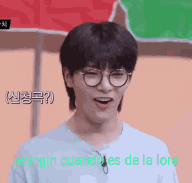 a young man wearing glasses and a blue shirt is smiling and making a funny face .