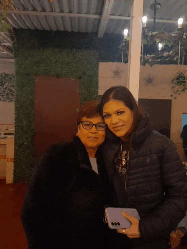 two women posing for a picture with one wearing a jacket that says the north face on it