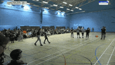 a group of roller derby players on a court with a scoreboard that says london roller derby