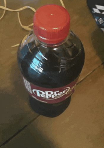 a bottle of dr pepper is on a wooden table