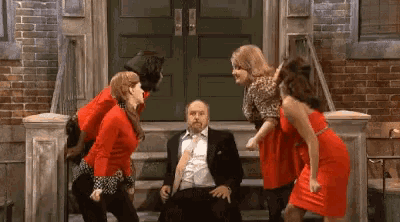 a man in a wheelchair is surrounded by three women in red dresses