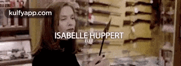 a woman is holding a knife in front of a wall of knives .