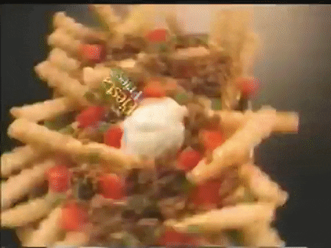 a close up of a stack of french fries with salsa and sour cream on top .