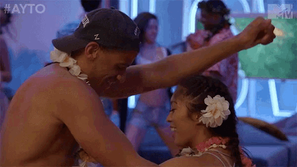 a man and a woman are dancing together at a party . the woman has flowers in her hair .