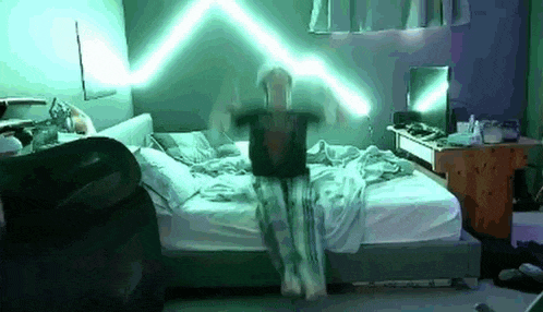 a person is standing on a bed with a laptop on their lap