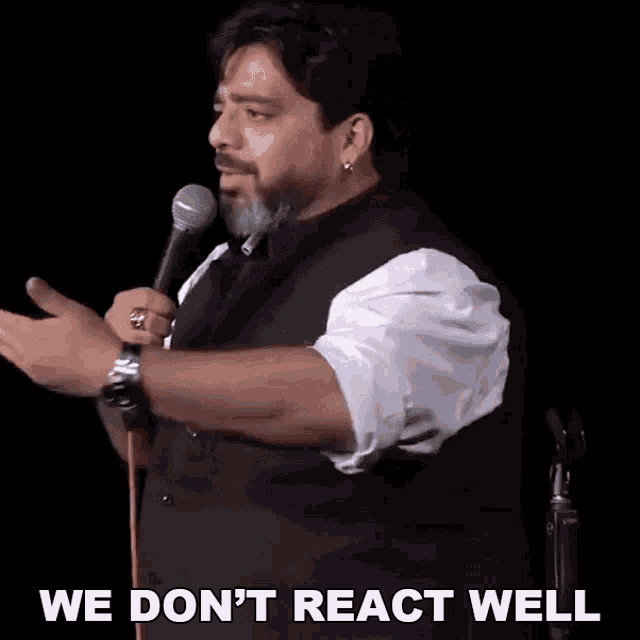 a man speaking into a microphone with the words " we don 't react well " written below him