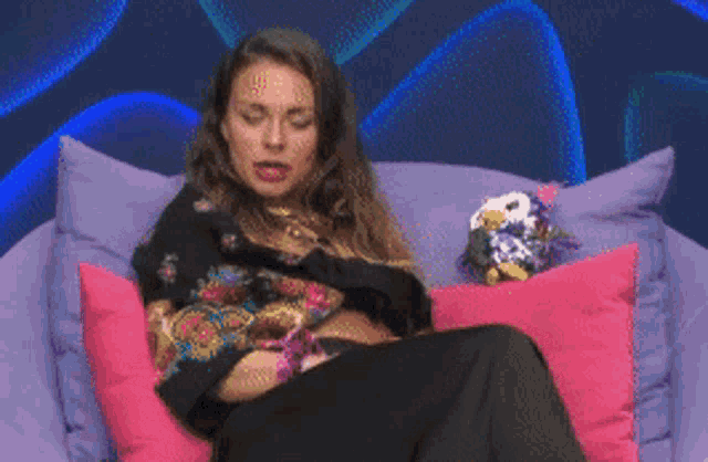 a woman is sitting on a couch with a stuffed penguin on it