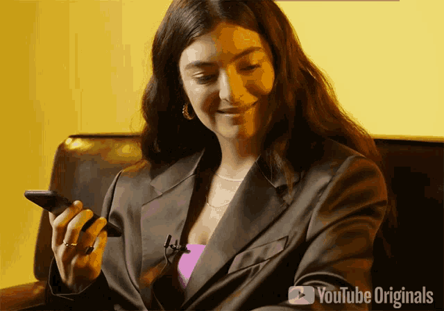 a woman is sitting on a couch looking at her phone with youtube originals written on the bottom