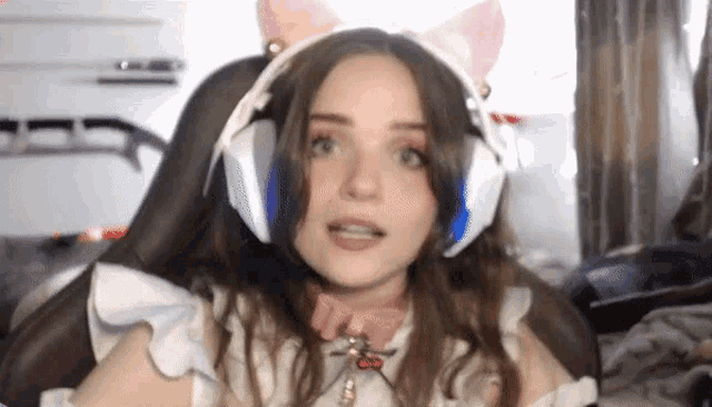 a woman wearing headphones and a cat costume is sitting in a chair and making a funny face .