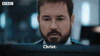 a man with a beard is saying christ in front of a computer screen
