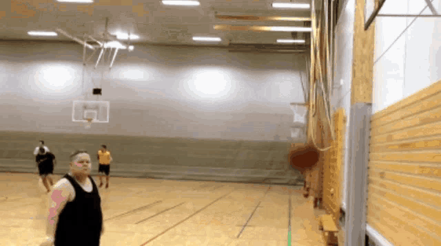 a man in a black tank top is playing basketball in an empty gym
