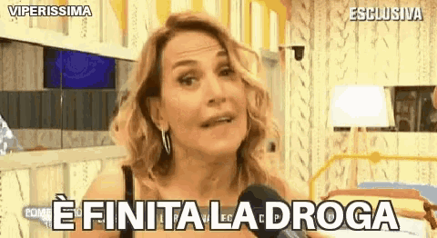 a woman is talking into a microphone and saying e finita la droga .