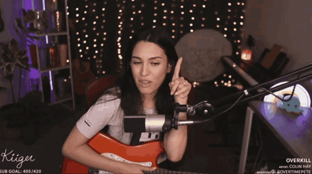 a woman playing a guitar in front of a microphone with the name kiiger on the bottom right