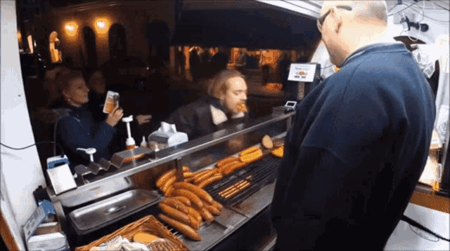a man standing in front of a display of hot dogs with a sign that says ' frankfurter ' on it