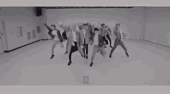 a black and white photo of a group of people dancing in a room .