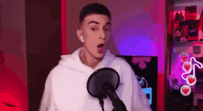a young man is singing into a microphone while wearing headphones .