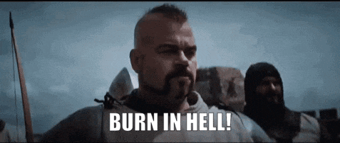 a man with a beard is standing in front of a group of men and says burn in hell !