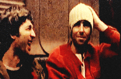 a man wearing a knitted hat laughs with another man