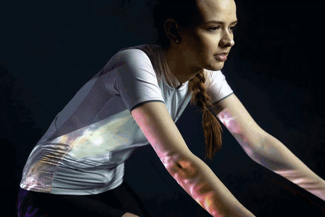 a woman wearing a white shirt and black shorts is standing in a dark room with her arms outstretched