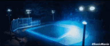 a basketball court is lit up at night with a lot of lights .