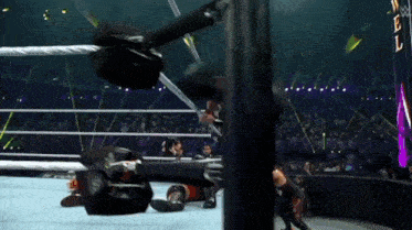 a wrestling match is going on in a ring with a rope hanging from the ropes