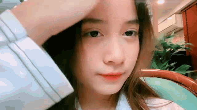 a girl is sitting in a chair with her hand on her head .