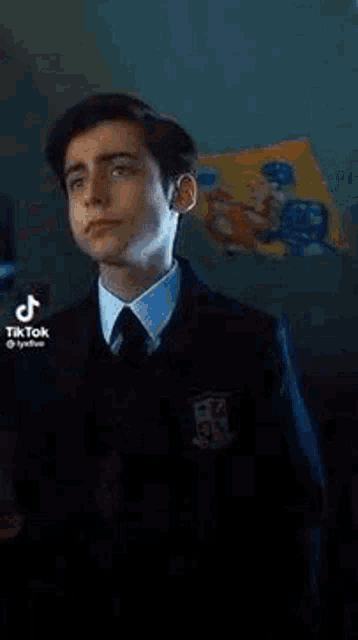 a young man in a suit and tie is standing in front of a blue wall .