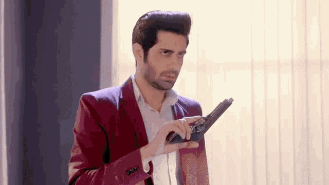 a man in a red jacket is holding a gun .