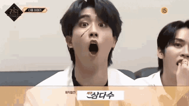 a man is making a funny face with his mouth open while another man looks on .