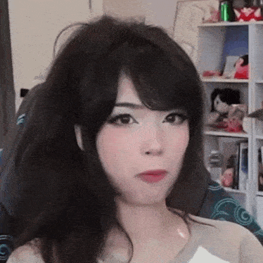 a close up of a woman making a funny face while sitting in front of a bookshelf .